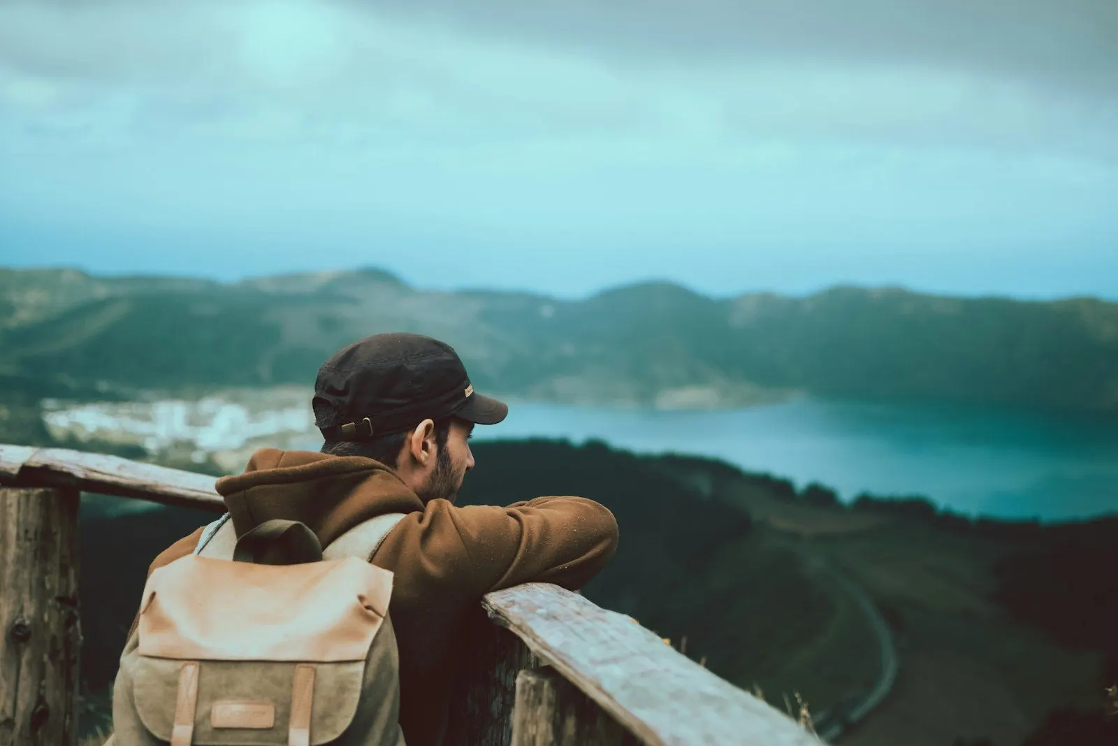 Viajero con mochila mirando un lago desde un mirador